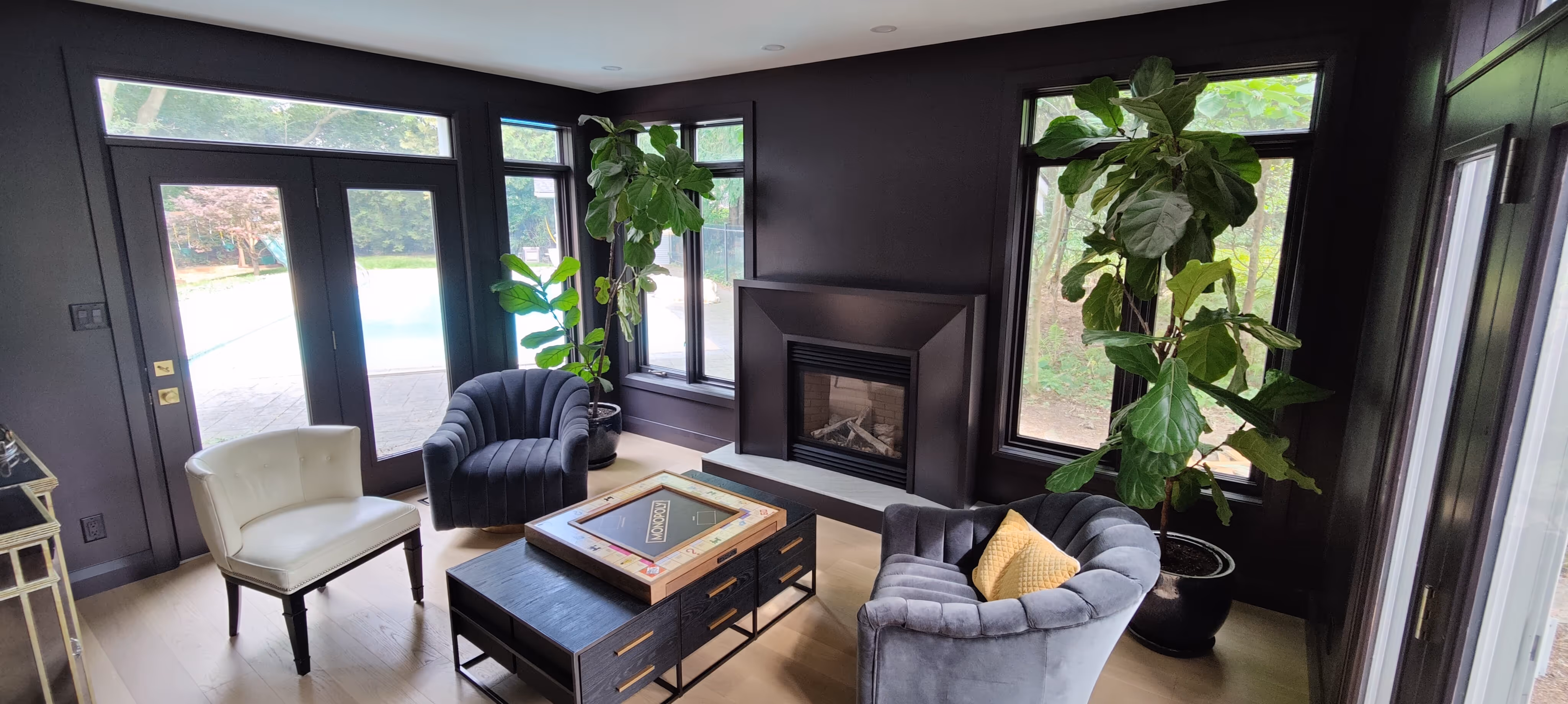 Modern living room renovation with custom black millwork, large windows, and a sleek fireplace — elegant interior carpentry by JB Carpentry.