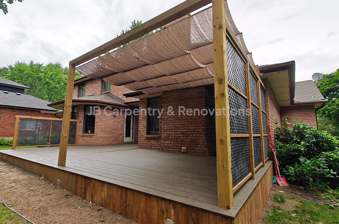 Custom-built backyard deck with wooden privacy panels and shade canopy — outdoor living renovation by JB Carpentry & Renovations.