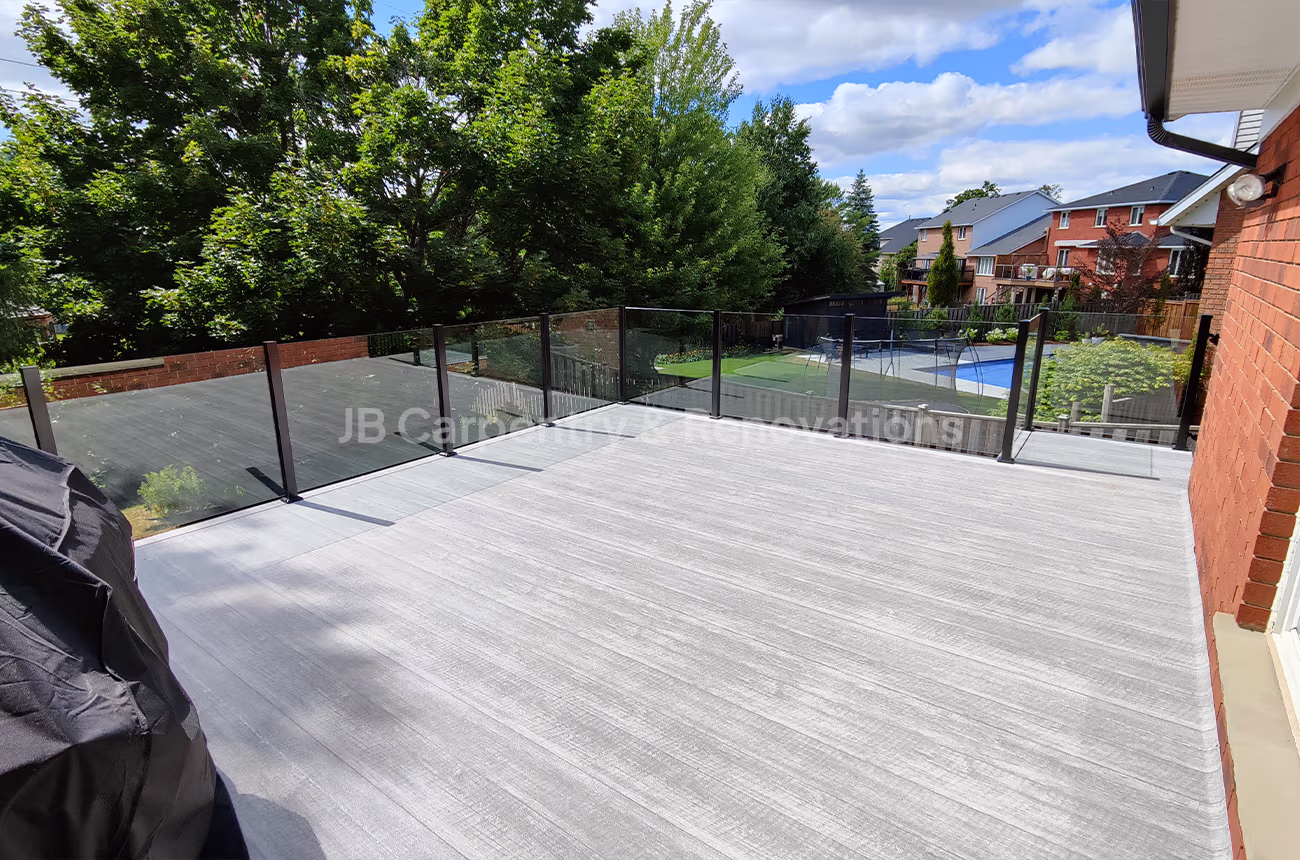 Elevated outdoor deck with modern glass railing and composite flooring — custom-built by JB Carpentry & Renovations.