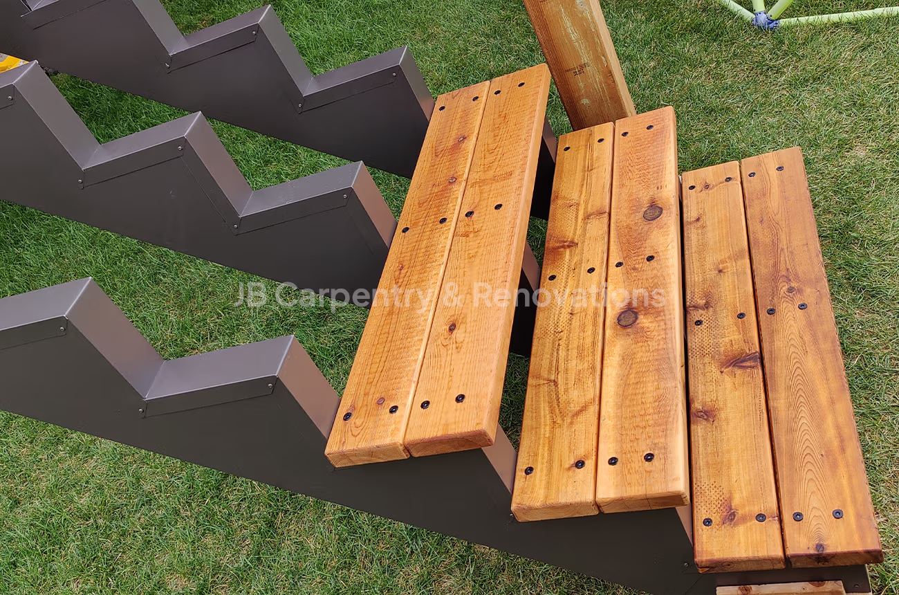 Close-up of custom-built deck staircase with powder-coated steel stringers and stained wood treads — precision exterior carpentry by JB Carpentry & Renovations.