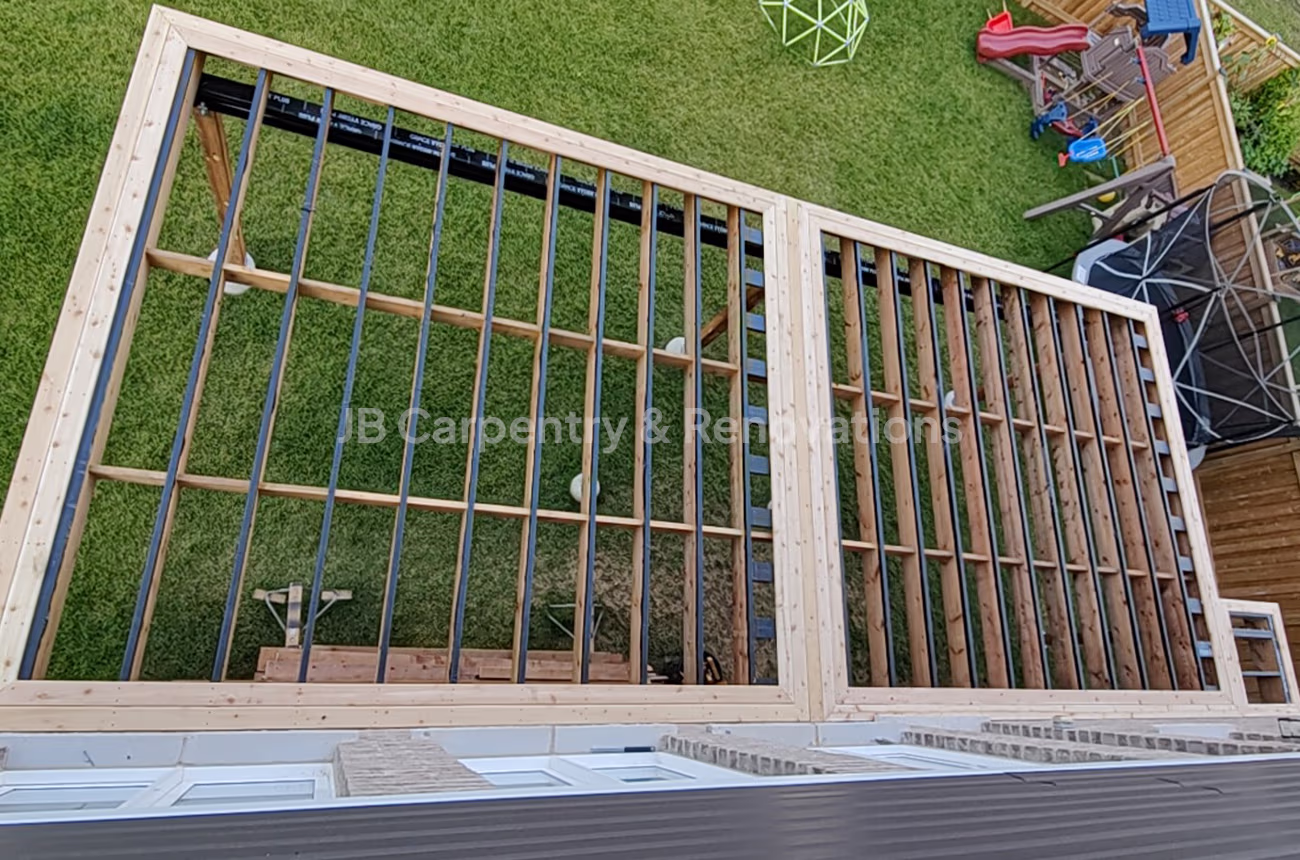 Overhead view of custom deck framing in progress, showing pressure-treated lumber and joist layout — structural carpentry by JB Carpentry & Renovations.
