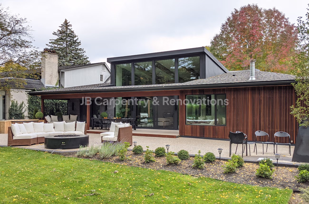 Custom exterior renovation with vertical wood siding and outdoor living area – Mid-century inspired home with warm wood cladding, full-height windows, and outdoor entertaining space.