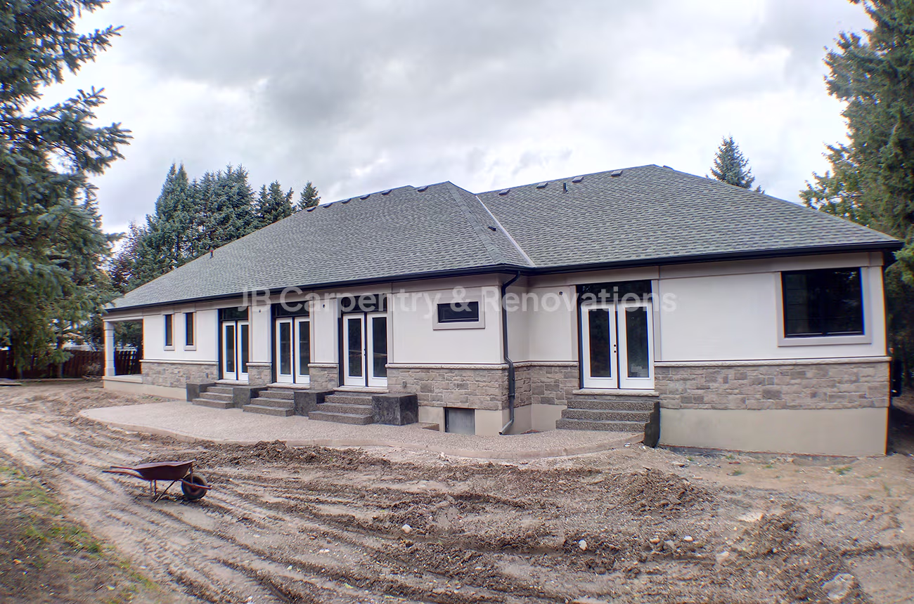 Large residential exterior renovation with new patio foundation, stone base, and French doors — construction by JB Carpentry & Renovations.