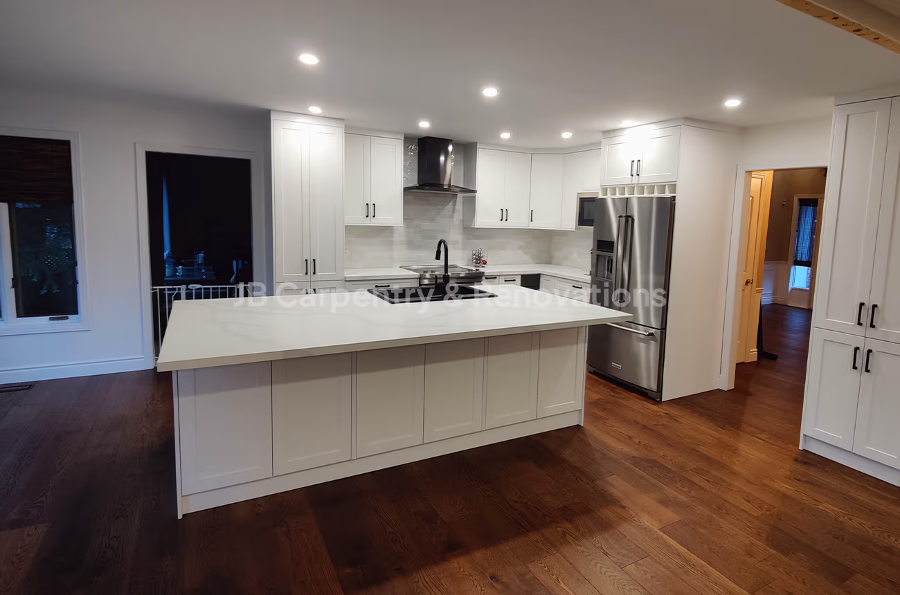 Spacious open-concept kitchen featuring white shaker cabinets, quartz countertops, and an integrated island — designed by JB Carpentry & Renovations.