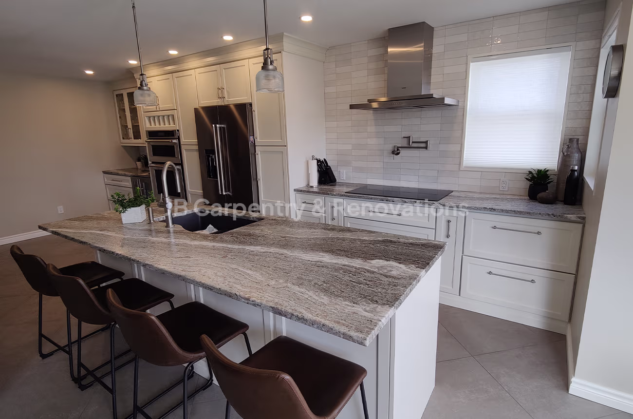 Luxury kitchen renovation featuring natural stone countertops, pendant lighting, and integrated stainless appliances — JB Carpentry & Renovations.