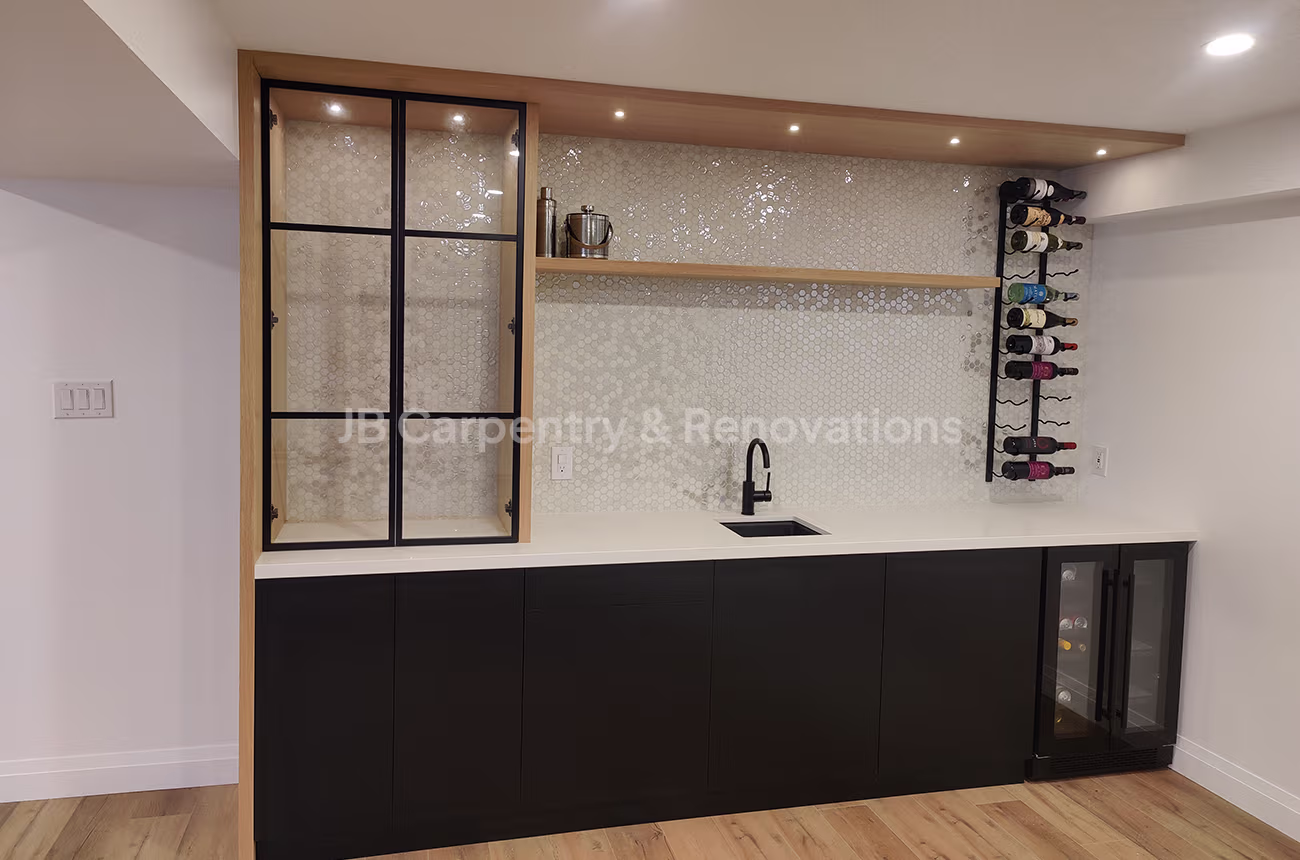 Modern home bar with black cabinetry, open shelving, glass display, and wall-mounted wine rack — JB Carpentry & Renovations.