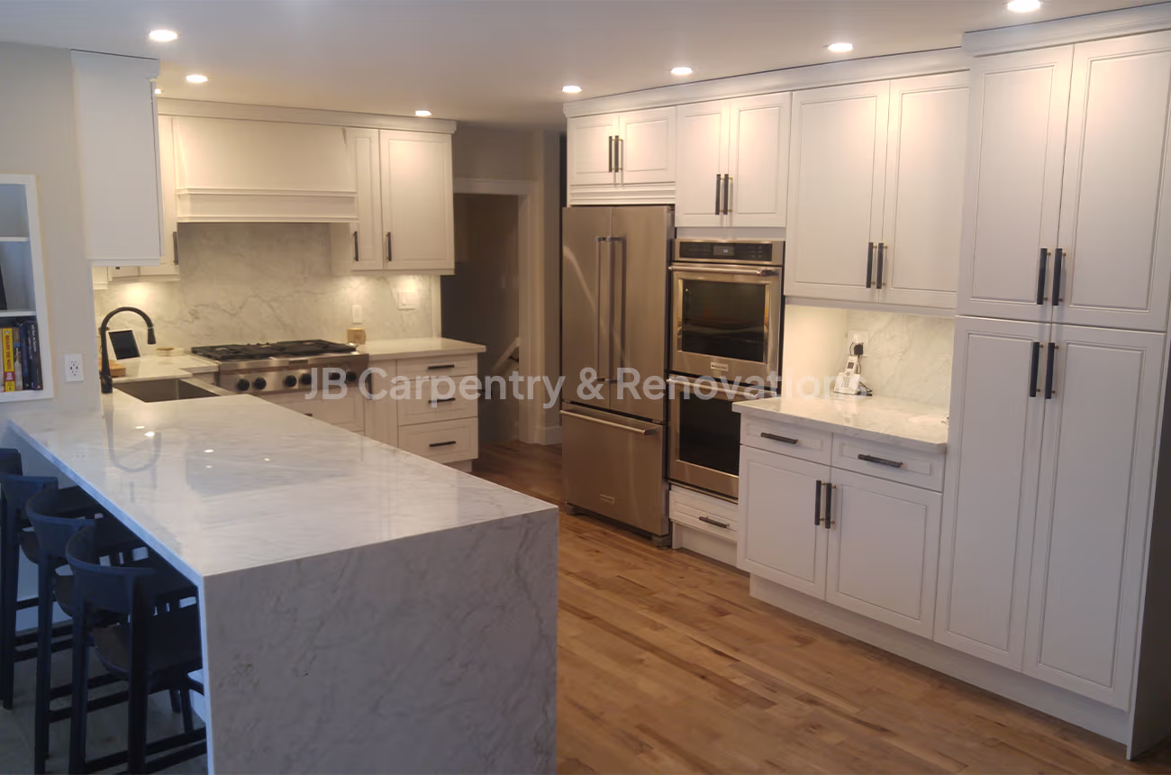 Elegant white kitchen with marble countertops, integrated appliances, and shaker cabinetry — JB Carpentry & Renovations.