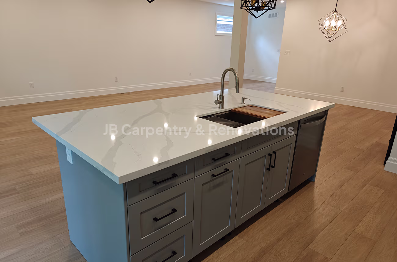 Modern basement kitchenette with grey cabinetry, quartz countertop, and integrated sink — JB Carpentry & Renovations.