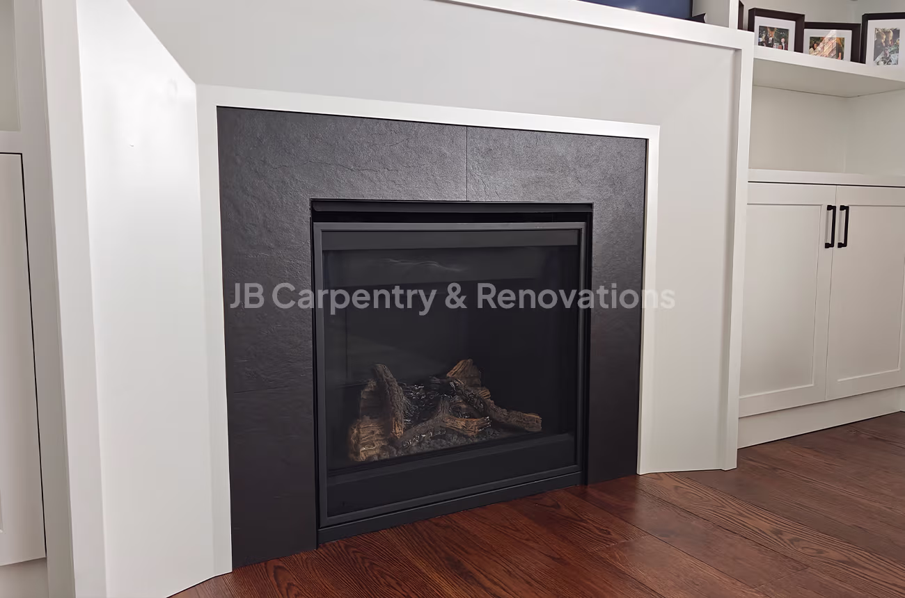 Custom fireplace surround with black tile and white cabinetry – Modern fireplace design with a matte black tile surround, white trim, and built-in cabinets on both sides.
