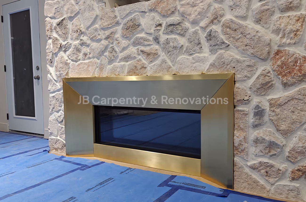 Stone fireplace with brushed brass surround – Feature fireplace with natural stone wall and striking brushed brass metal surround.