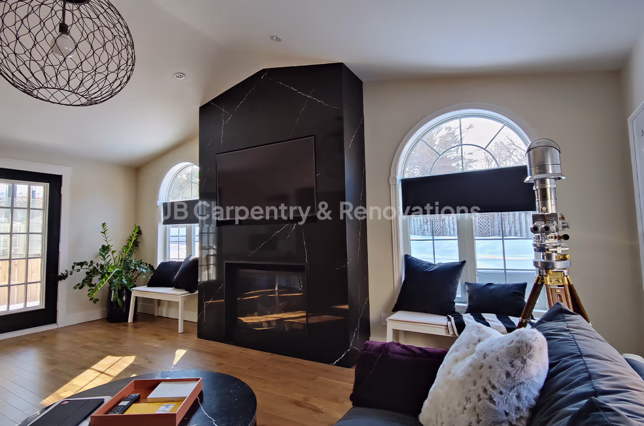 Black marble fireplace wall with mounted TV – Luxury living room with a floor-to-ceiling black marble fireplace surround, integrated TV mount, and arched windows.