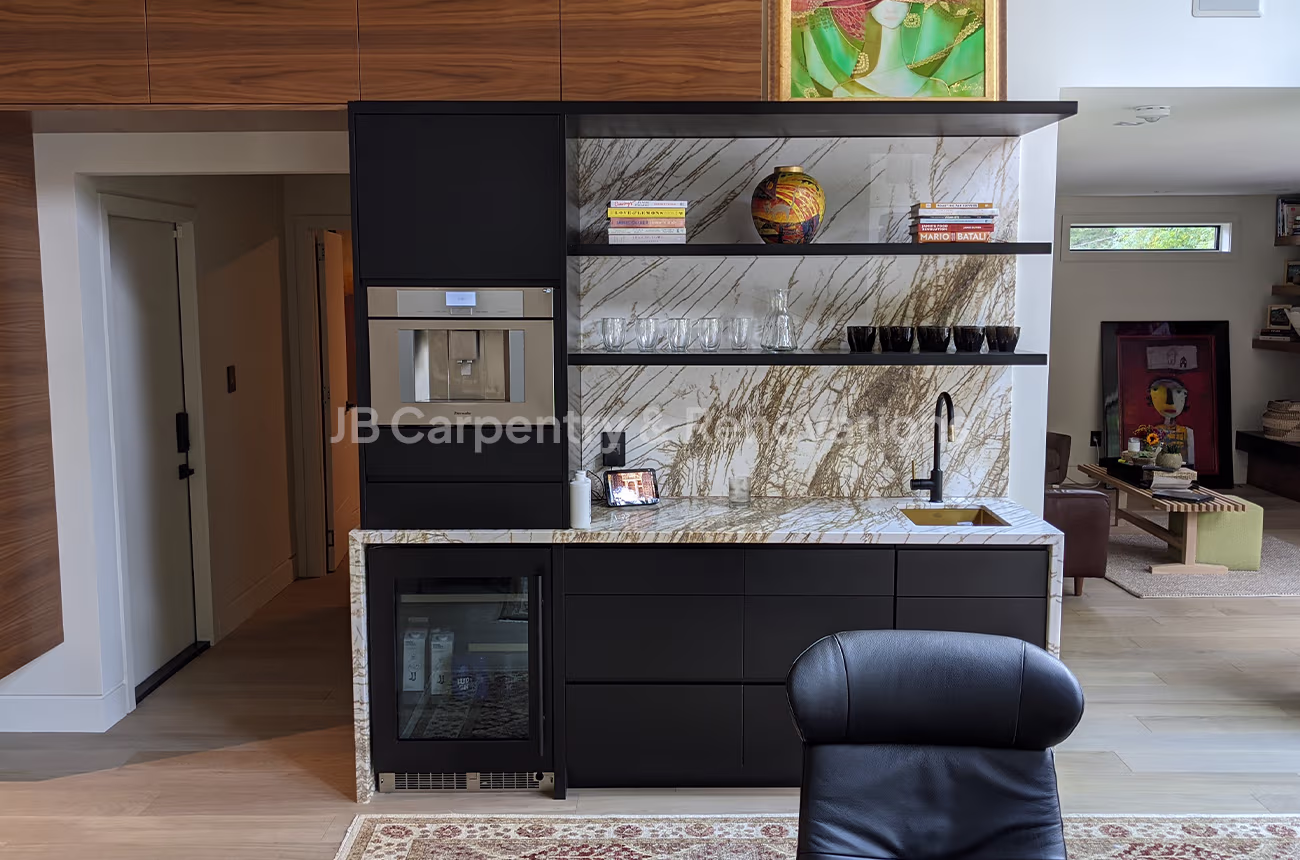 Modern home bar with marble backsplash and black cabinetry – Custom wet bar with veined marble backsplash, floating glass shelves, matte black cabinetry, and built-in beverage fridge.
