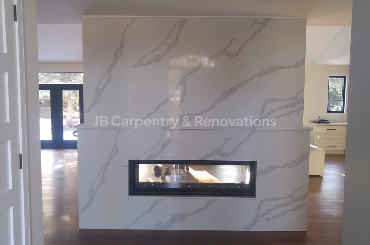 Linear marble fireplace feature wall – Modern living space with a full-height marble-look porcelain wall and linear gas fireplace insert.