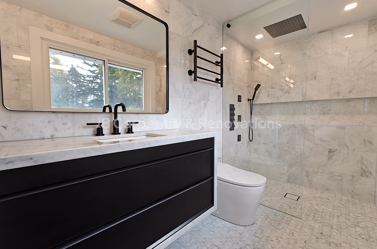Marble bathroom with black fixtures and glass shower – Contemporary bathroom featuring a black vanity, matte black faucet, and rainfall shower in a marble-tiled space.