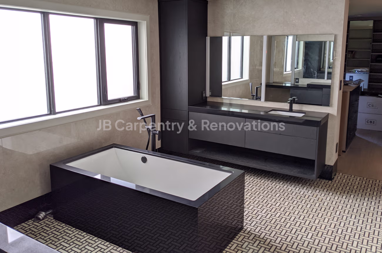 Modern bathroom with black bathtub and vanity – Sleek bathroom featuring a black freestanding tub, matching black vanity, and geometric tile floor with large window light.