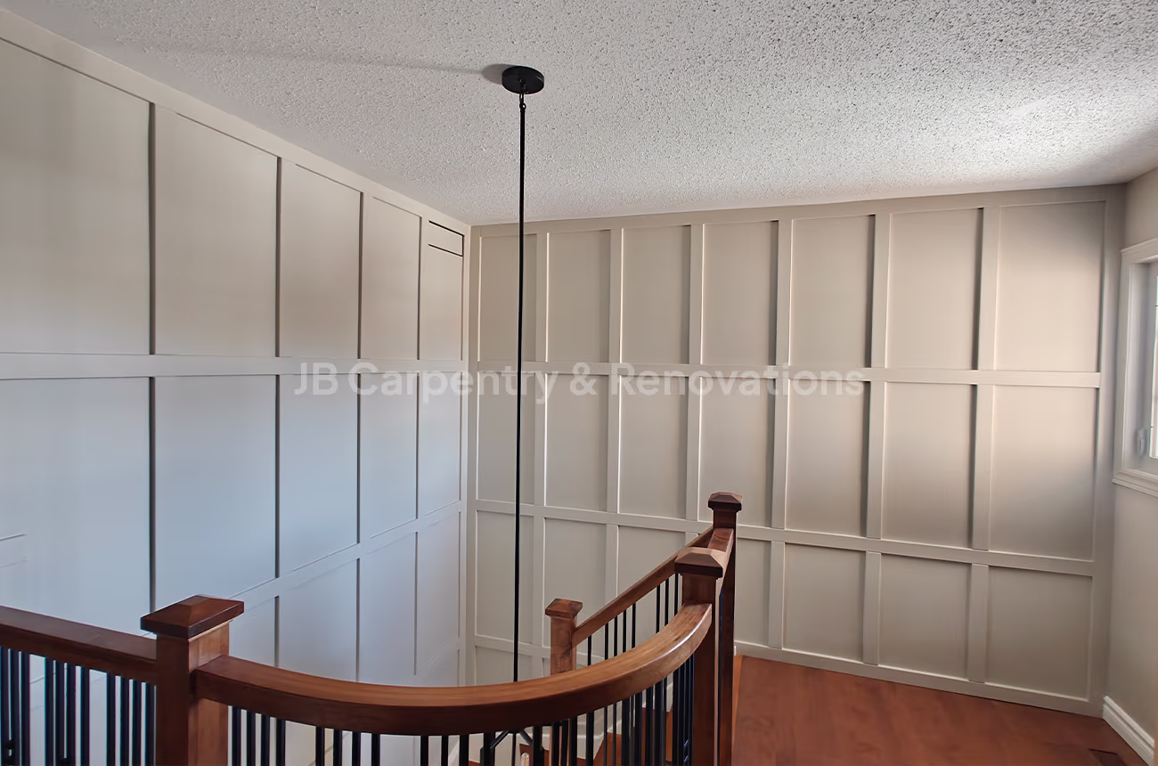 Stairwell with full wall paneling and wood railing – Bright upper landing showcasing detailed wall paneling and a curved wood railing.