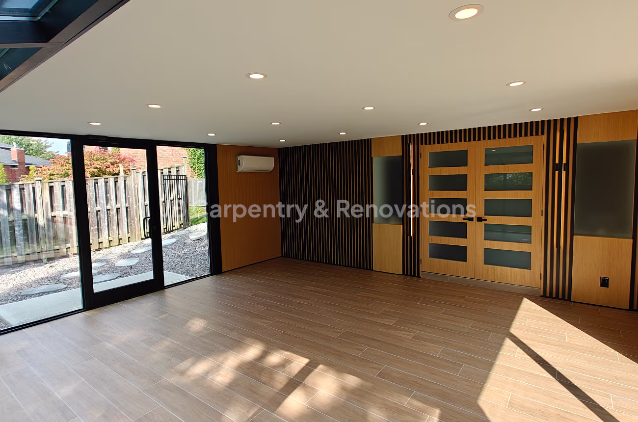 Contemporary sunroom with wood accents – Bright sunroom with large glass doors, black-and-wood slatted walls, and matching wood-panel double doors.