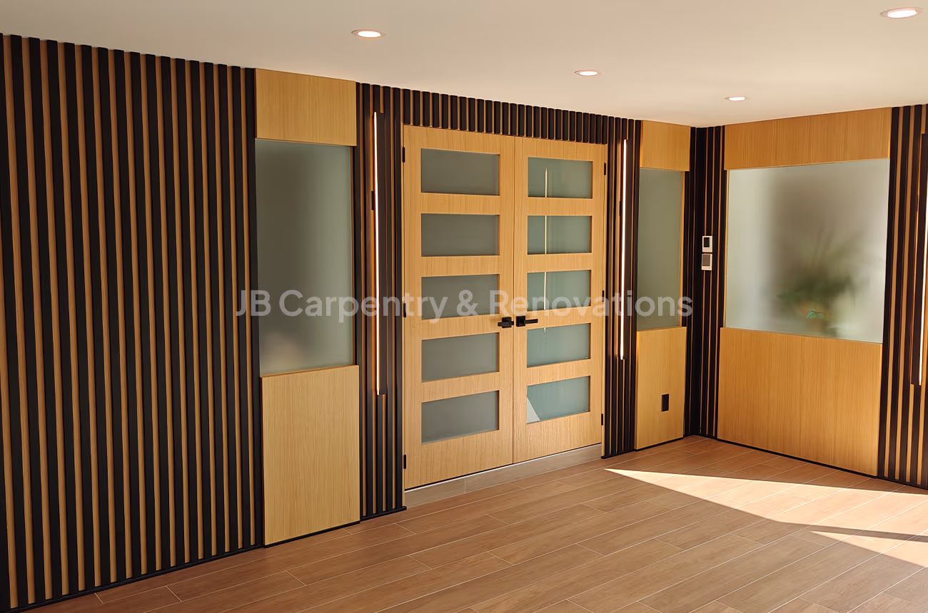 Modern entryway with black and wood wall design – Detailed view of wood and black slat wall with frosted glass panels and a modern double-door entry.