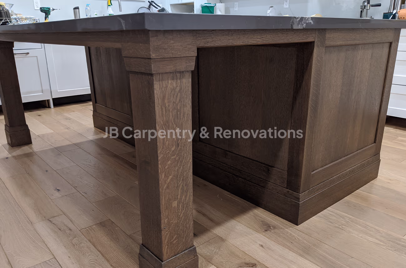 Rustic kitchen island with thick legs and stone countertop – Solid wood kitchen island with detailed legs, dark stain, and grey quartz countertop.