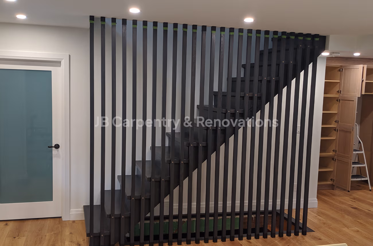 Contemporary staircase with vertical slat wall divider – Modern open-riser staircase enclosed by black vertical wood slats as a stylish feature wall.