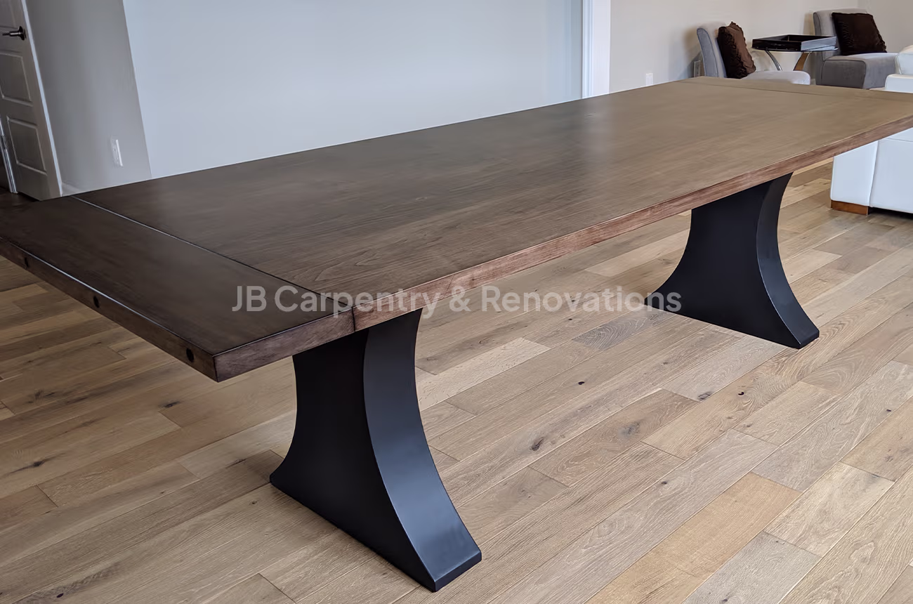 Dark-stained dining table with steel pedestal base – Contemporary hardwood dining table with dark finish and powder-coated steel bases.
