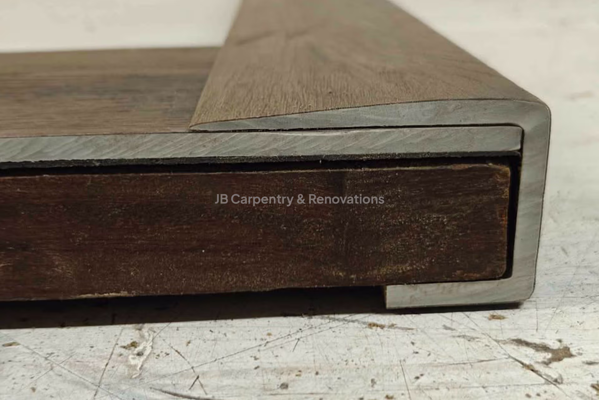 Custom metal-wrapped stair nosing edge detail – Cross-section view of a stair nosing with metal trim detailing over a solid wood core.