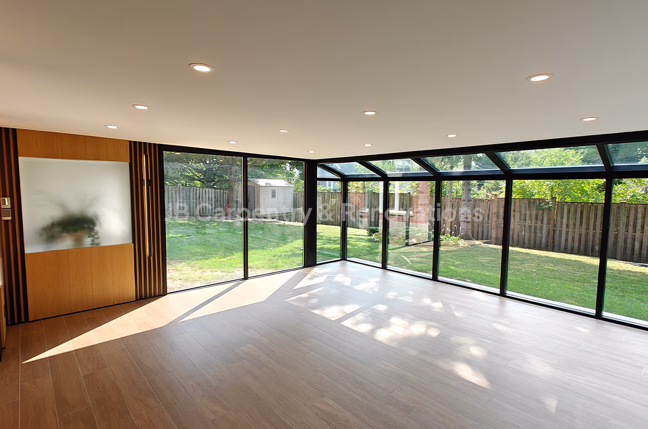 Bright sunroom with full glass walls overlooking backyard, built by JB Carpentry & Renovations.