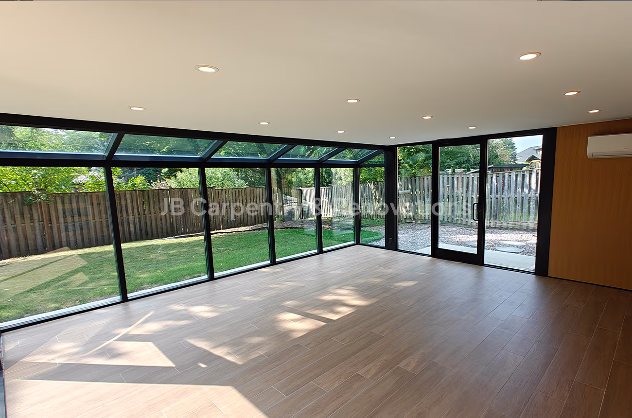 Spacious sunroom with tile flooring, glass ceiling panels, and sliding doors to backyard.