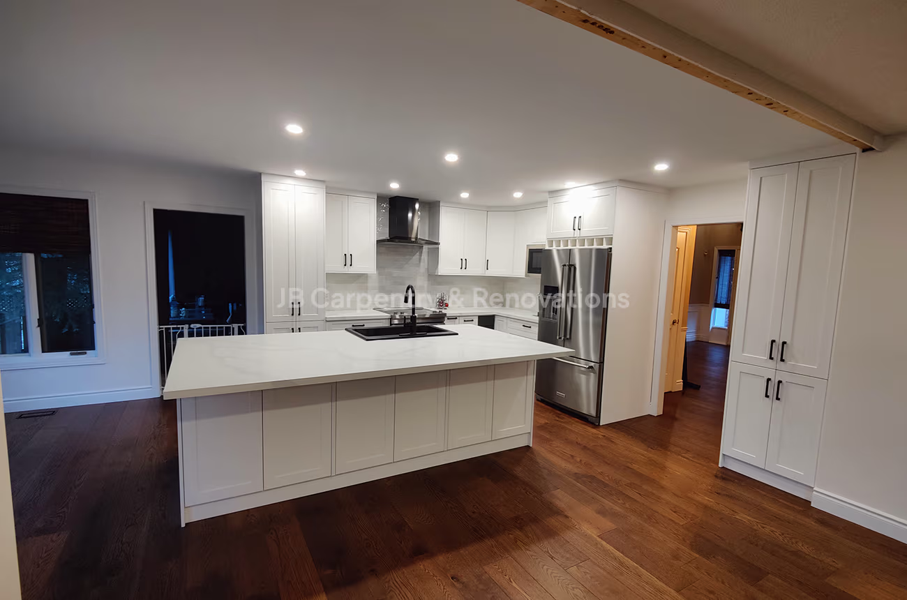 Spacious kitchen remodel featuring large island, shaker cabinets, and hardwood floors by JB Carpentry & Renovations.