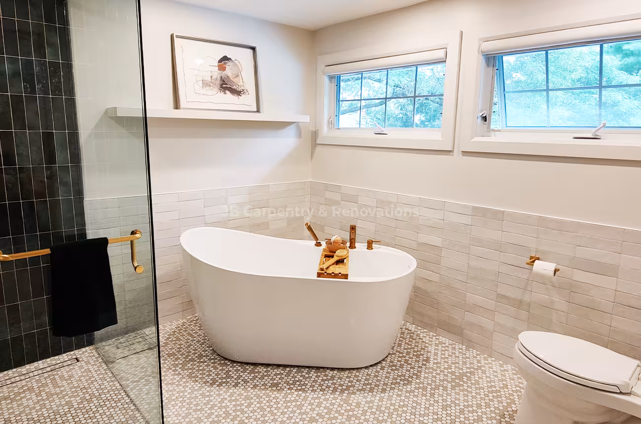 Modern bathroom with freestanding tub and natural light – Bright and serene bathroom space with white wall tile, gold accents, and large windows.