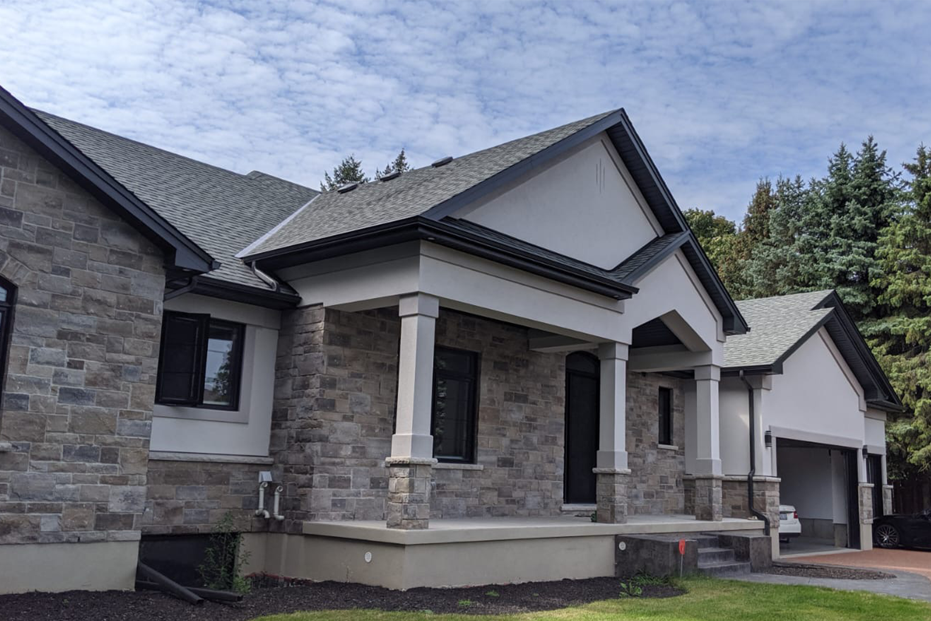 Luxury stone bungalow new build with classic gabled roof – Elegant single-story custom home with natural stone facade, detailed trim, and architectural columns.