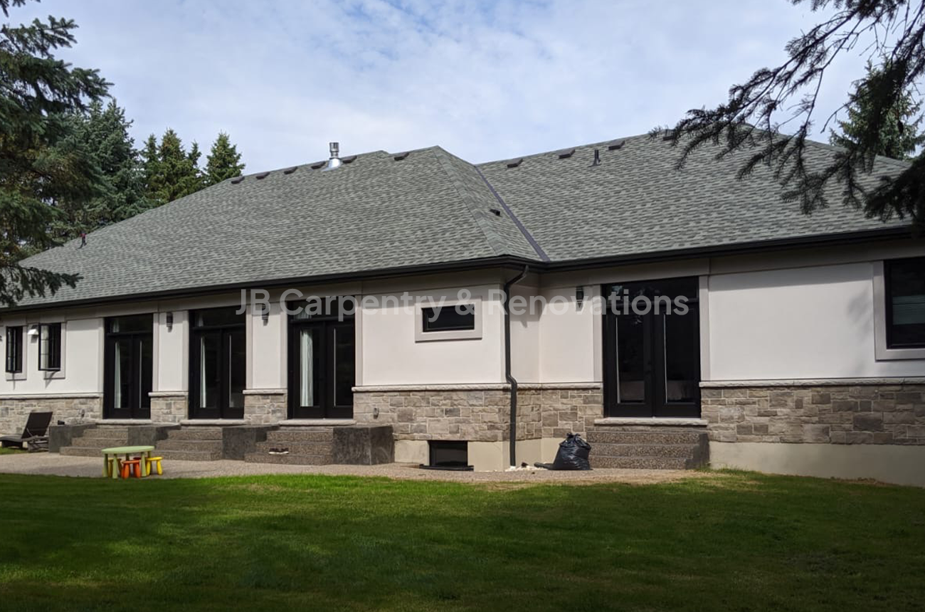 Bungalow new build with stone and stucco exterior – Elegant single-story new build showcasing light stucco walls, stone accents, and black window and door trim.
