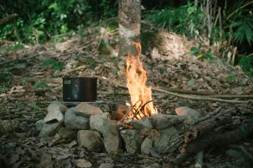 Feu de camp en forêt avec une casserole qui chauffe
