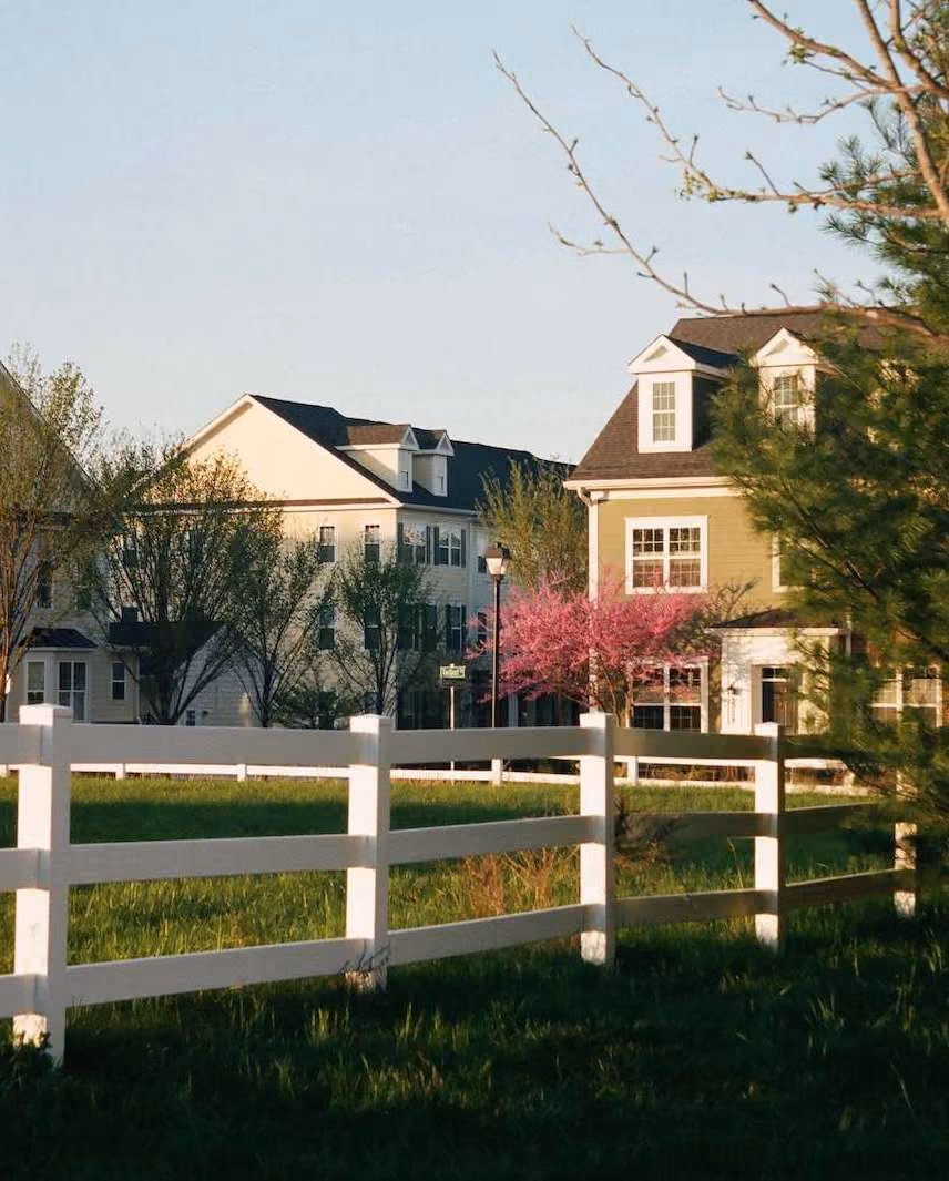 Photograph of a pretty house with a white picket fence in the sunshine. Buy a home with expert representation from The Home Buyers.