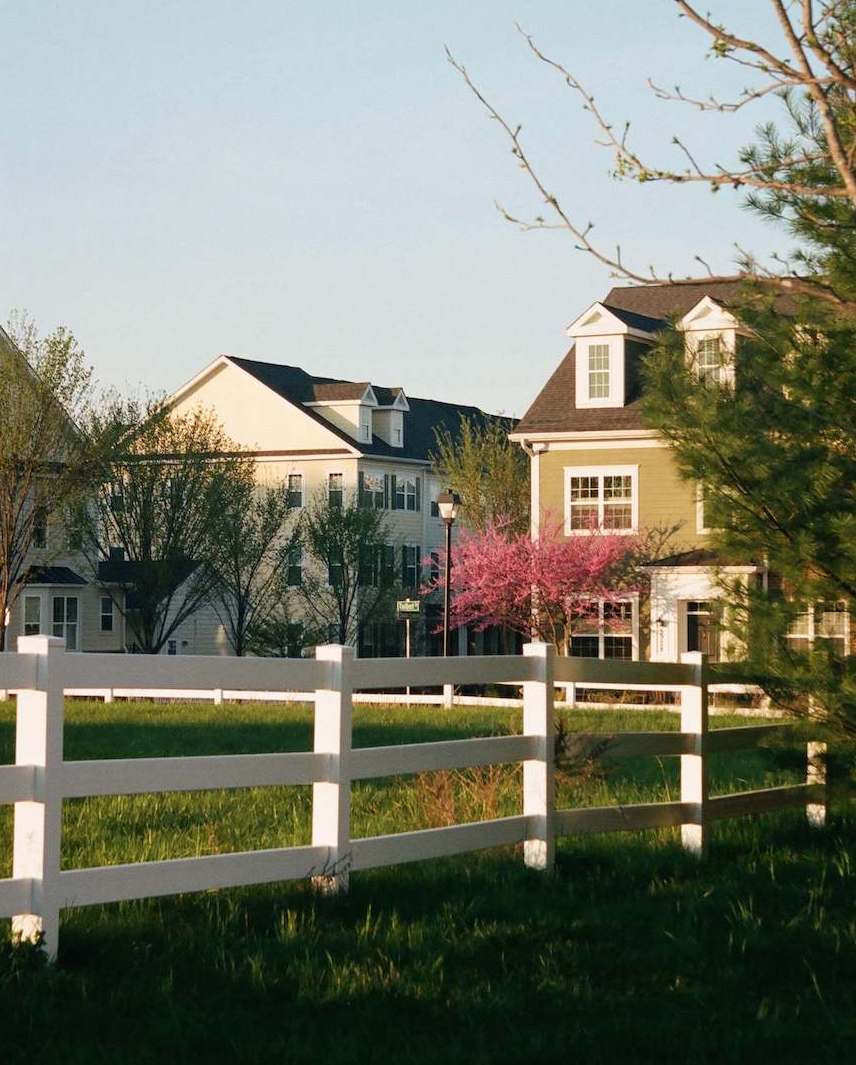 Photograph of a pretty house with a white picket fence in the sunshine. Buy a home with expert representation from The Home Buyers.