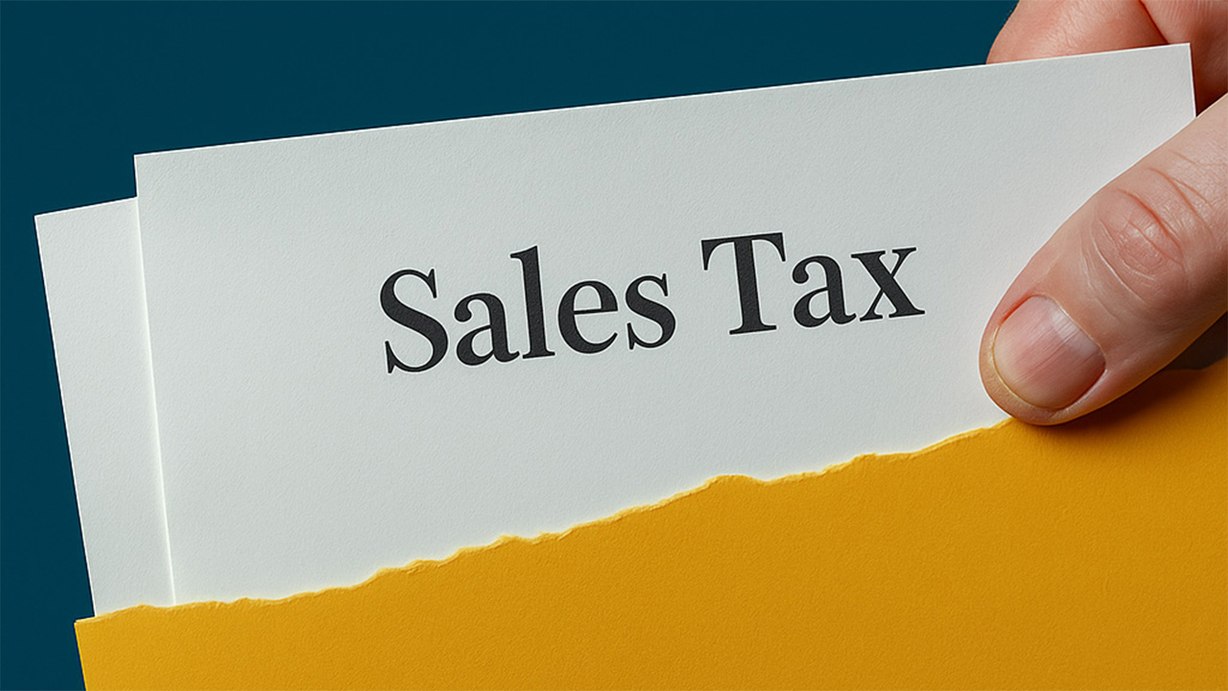 Hand holding a document labeled Sales Tax partially inside a yellow envelope.