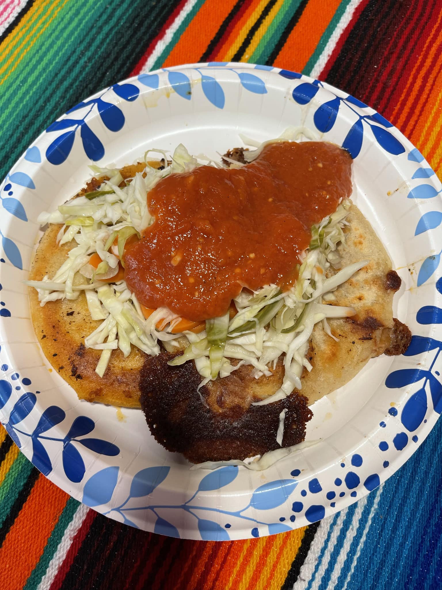 A plate filled with food rests on a lively, colorful tablecloth, creating a warm and inviting atmosphere for a meal.