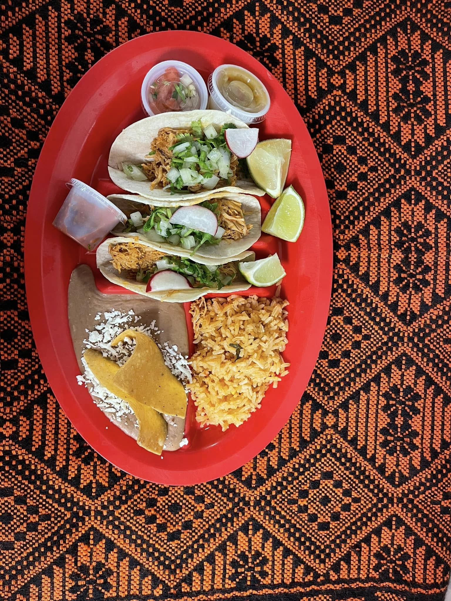 A plate of colorful food sits on a wooden table, showcasing a variety of dishes ready to be enjoyed.