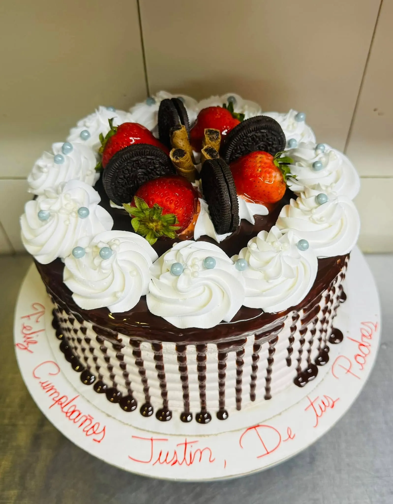 A rich chocolate cake topped with fresh strawberries and crushed Oreos, elegantly presented on a white plate.