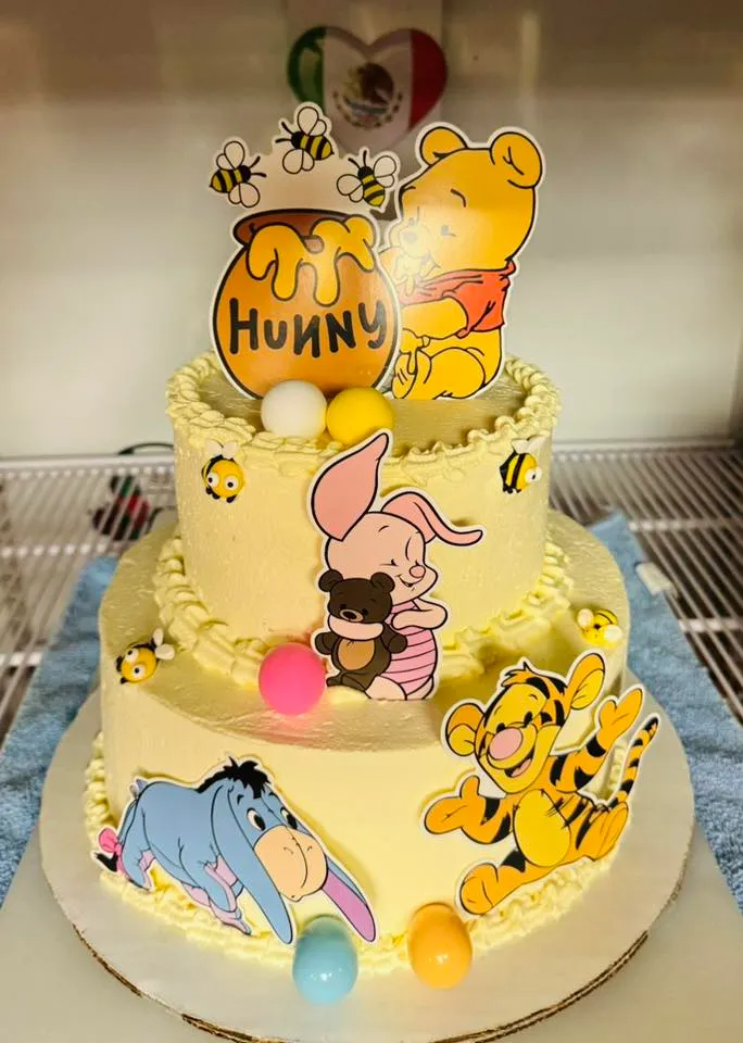 A whimsical Winnie the Pooh cake decorated with honey pots and cheerful colors, perfect for a child's birthday celebration.