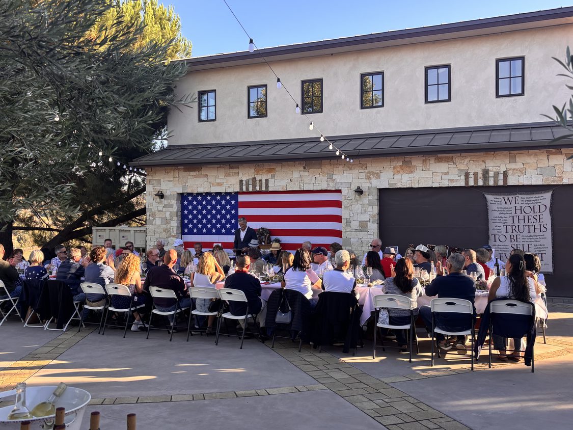 Long table set for winemaker dinner overlooking vineyard (AI)