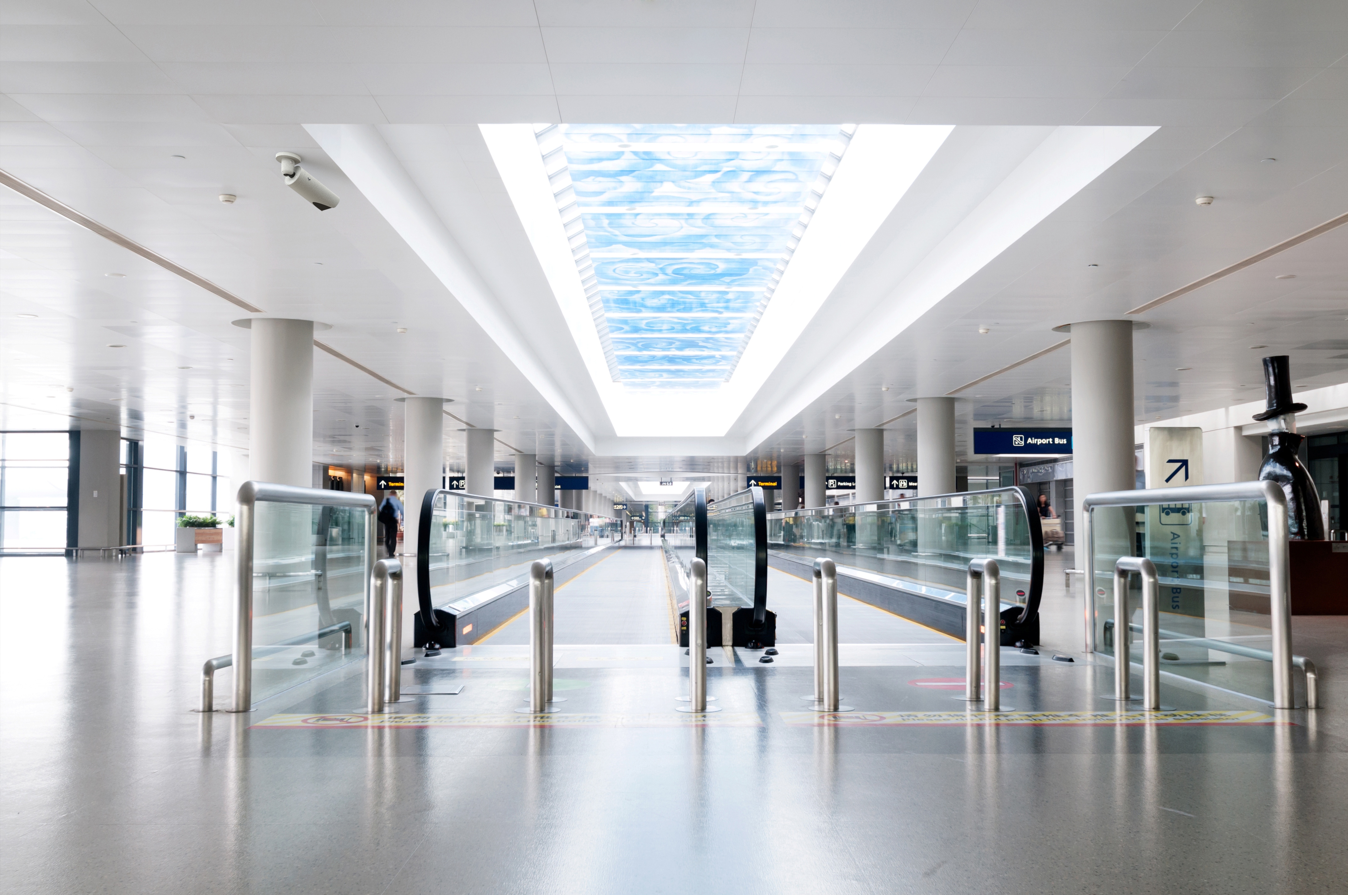 Empty airport corridor with moving walkways under a long skylight.