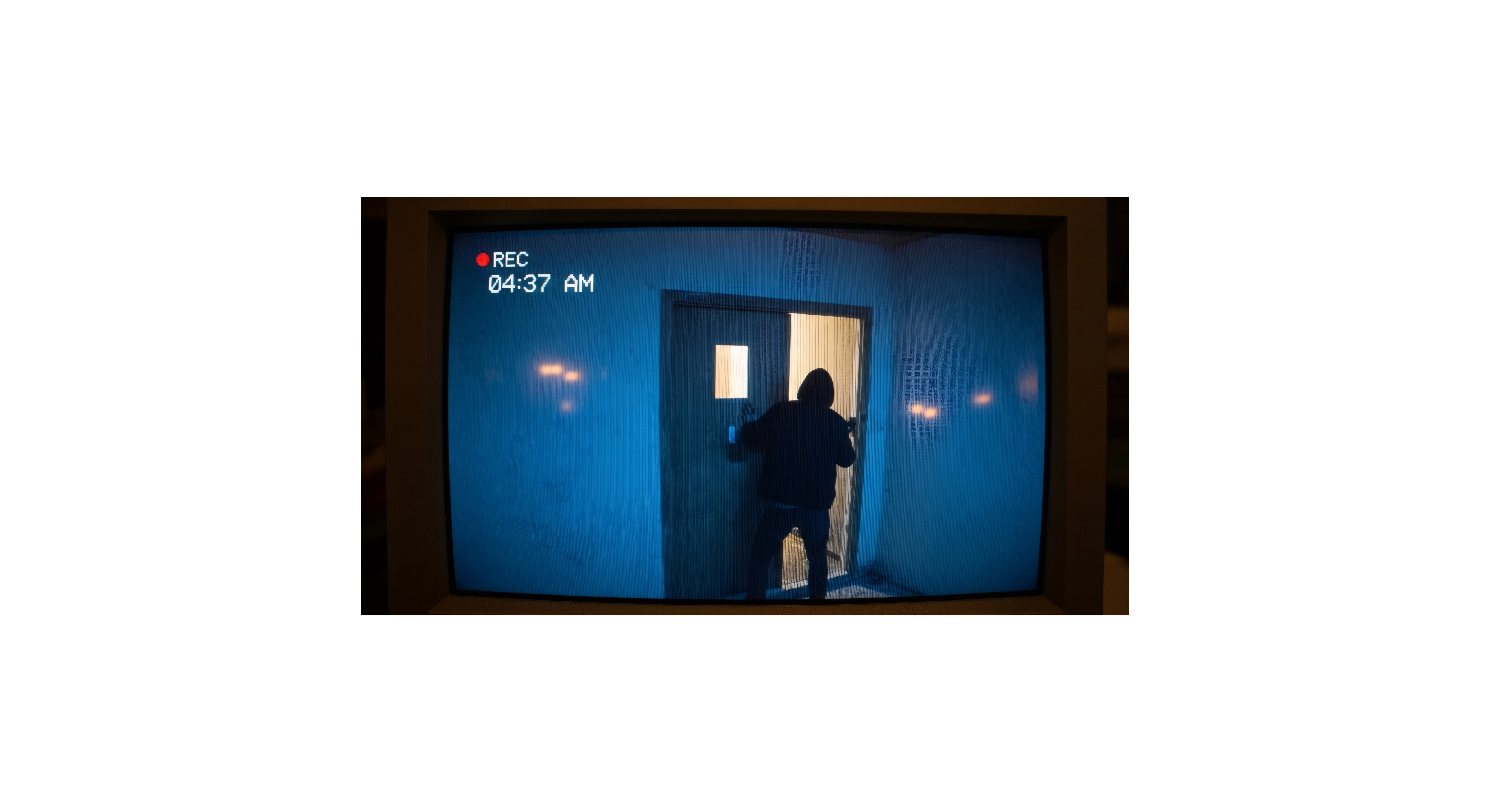 Surveillance camera footage showing a hooded person entering a door.