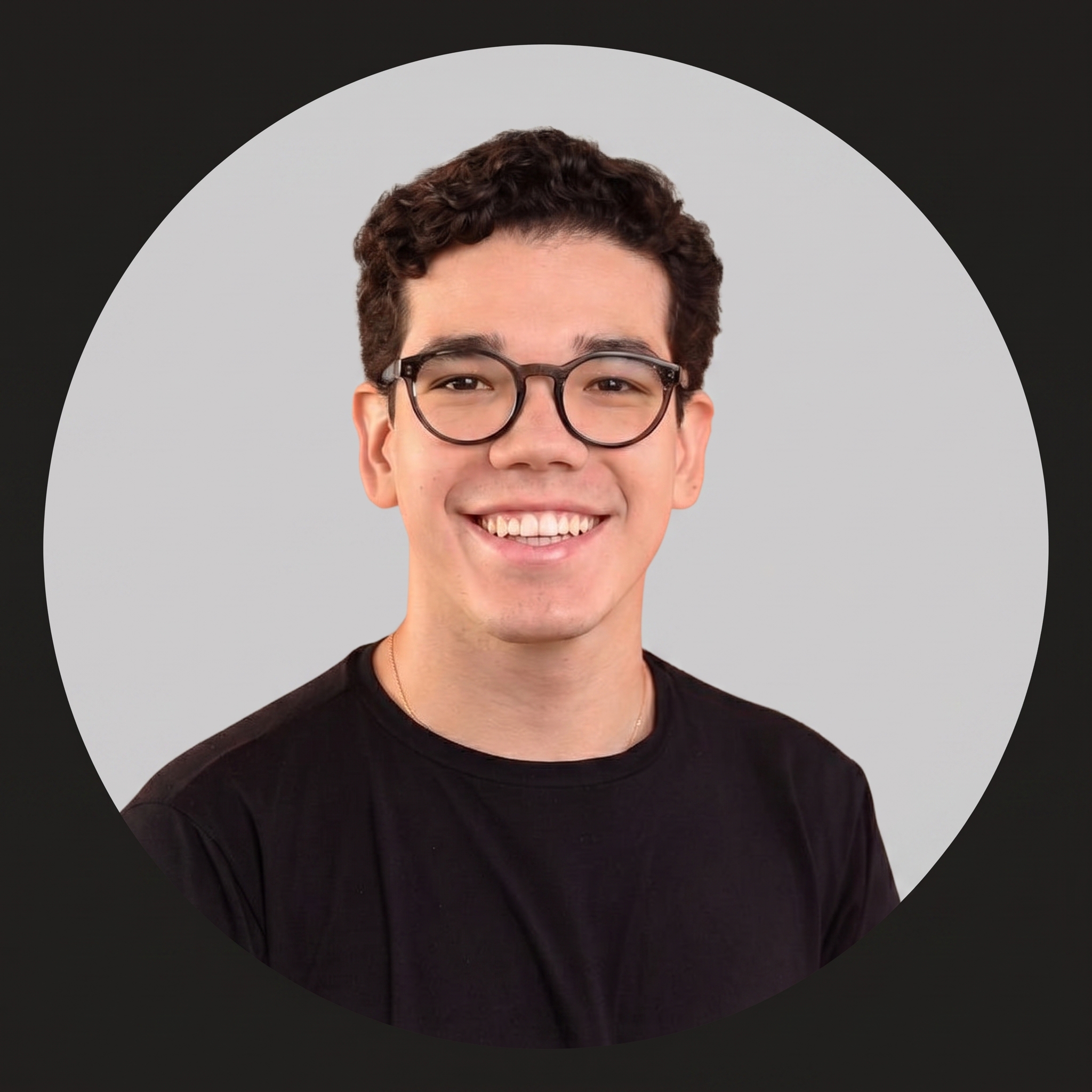 Photo of a smiling young man with curly hair and glasses, wearing a black t-shirt, against a plain gray circular background