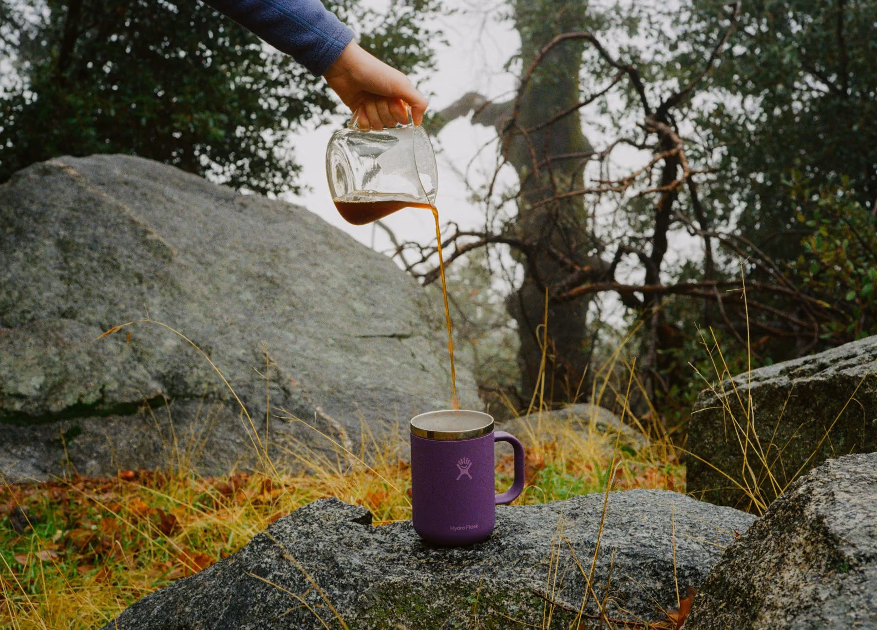 Hydroflask coffee thermos with UGC shot in a natural, outdoor setting.