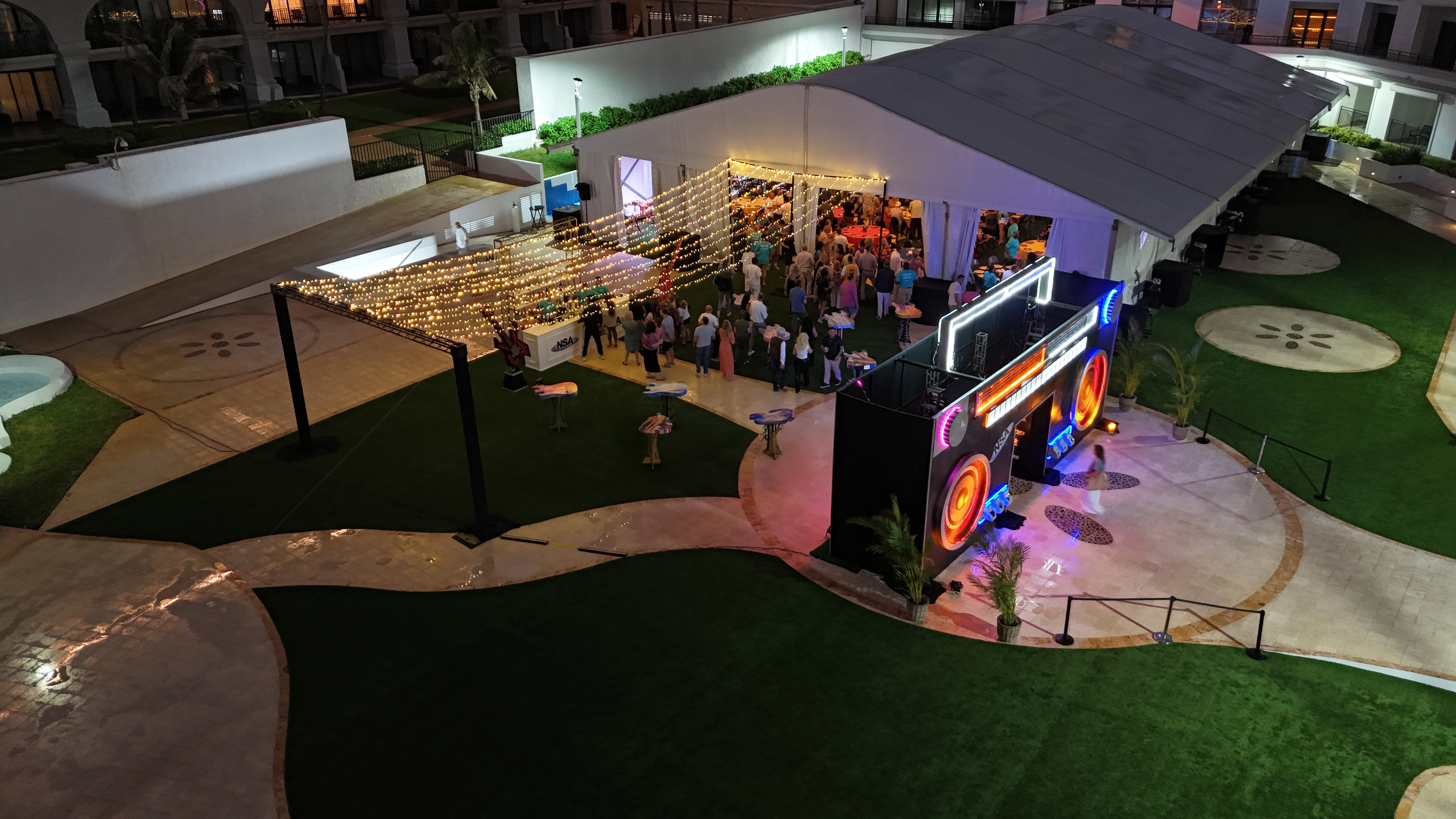 Drone photo taken at the event of the outdoor karaoke after-party with a custom boombox entryway, guitar-shaped cocktail tables and event tent.