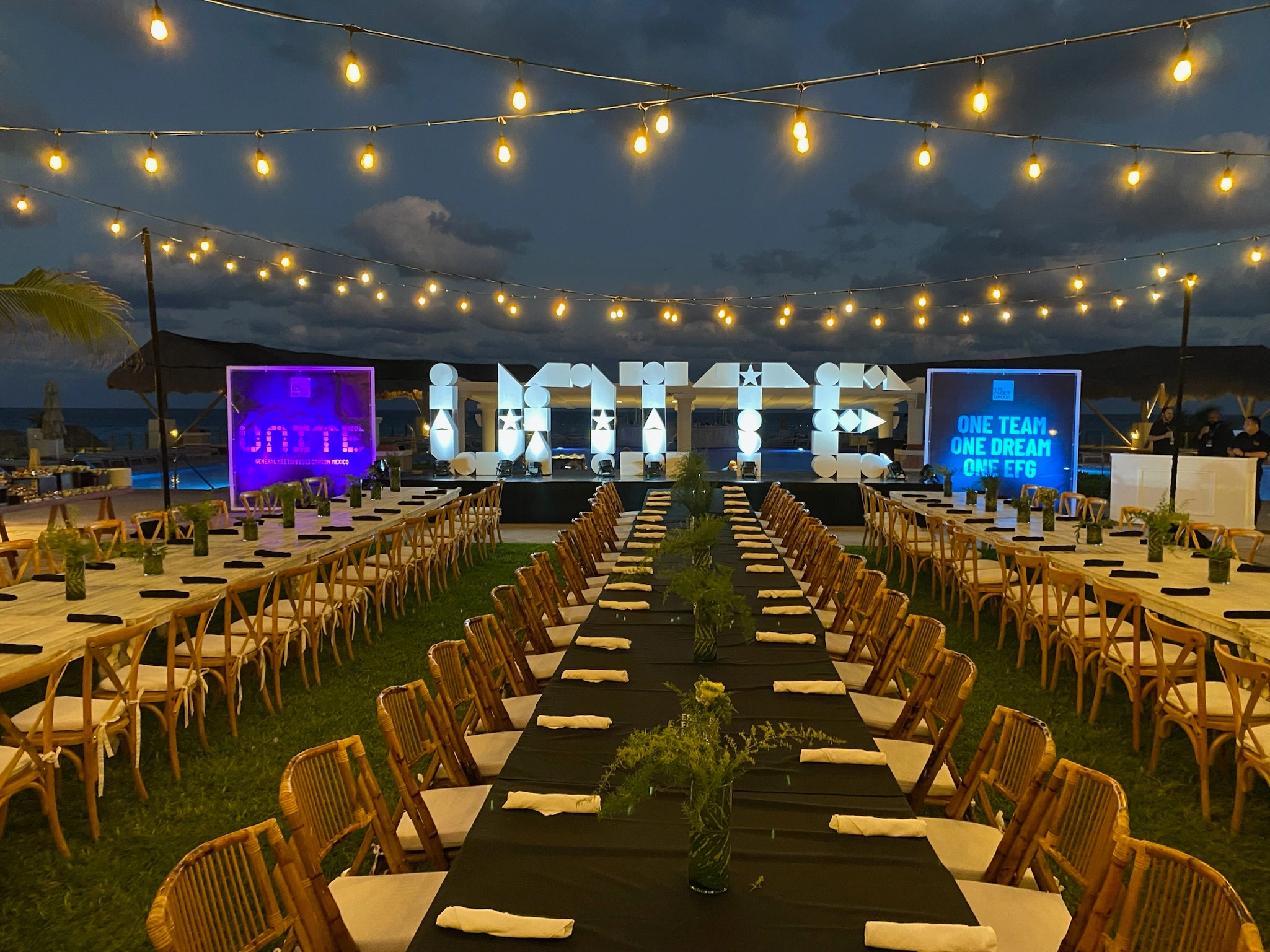 Long banquet tables arranged before illuminated UNITE letters during the conference welcome dinner.