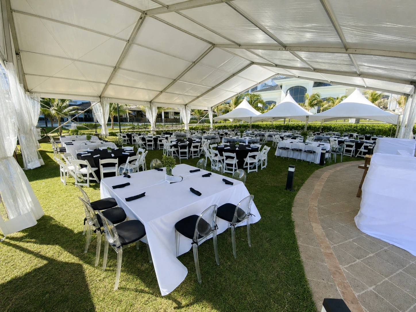 Guests dining beneath large white tents arranged around black and white breakfast tables.