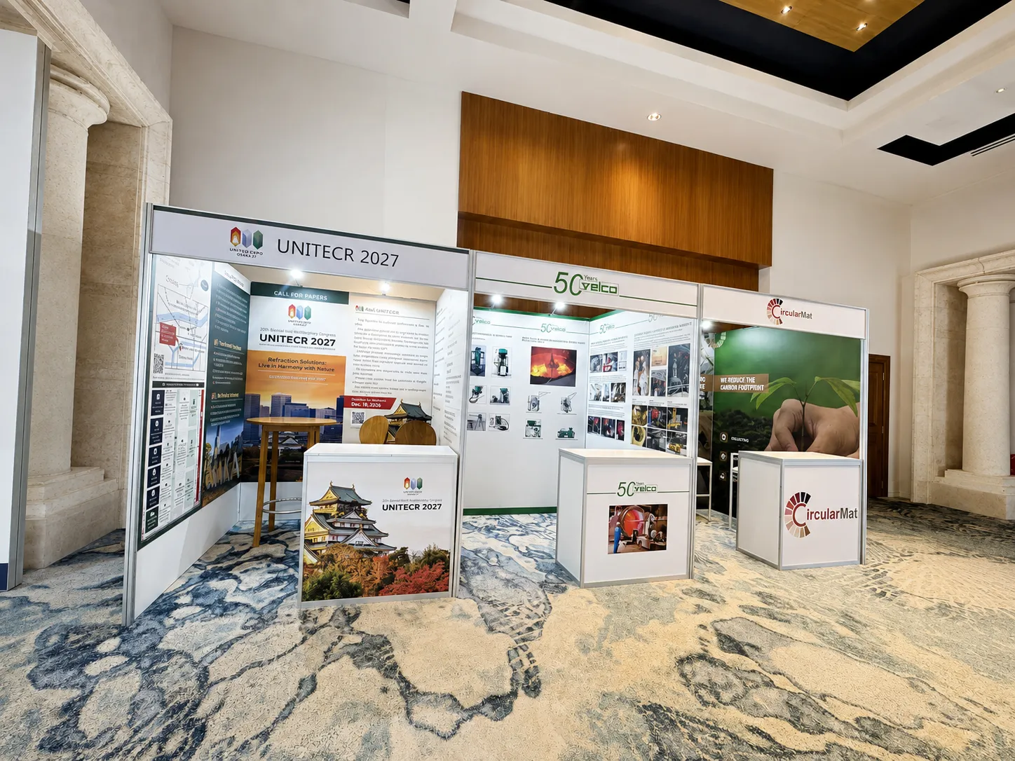 Finished row of modular expo booths with printed fabric graphics, counters, stools and product displays in a carpeted foyer.