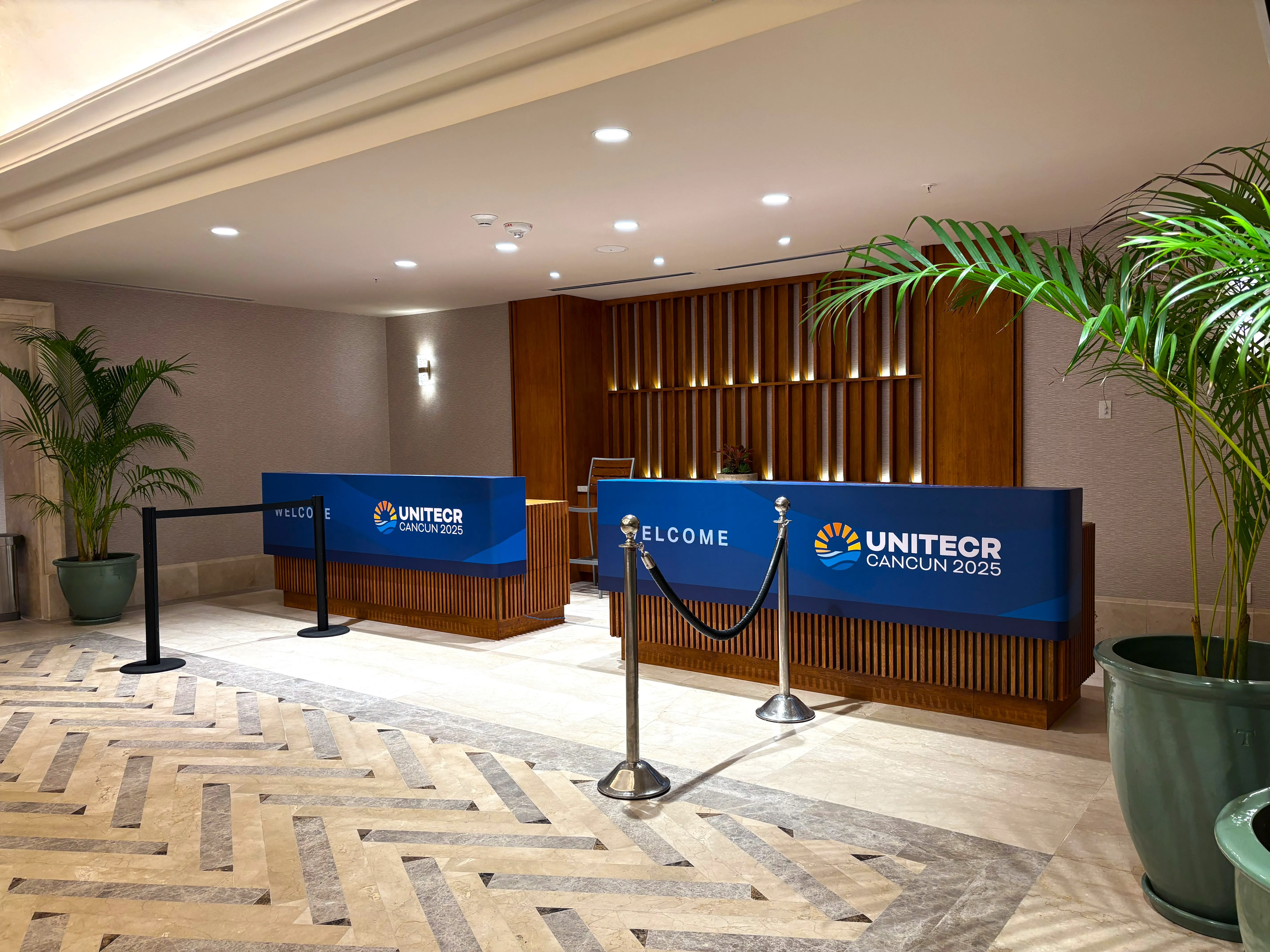 A reception desk wrapped in custom branded graphics with a welcome sign beneath wood paneling.